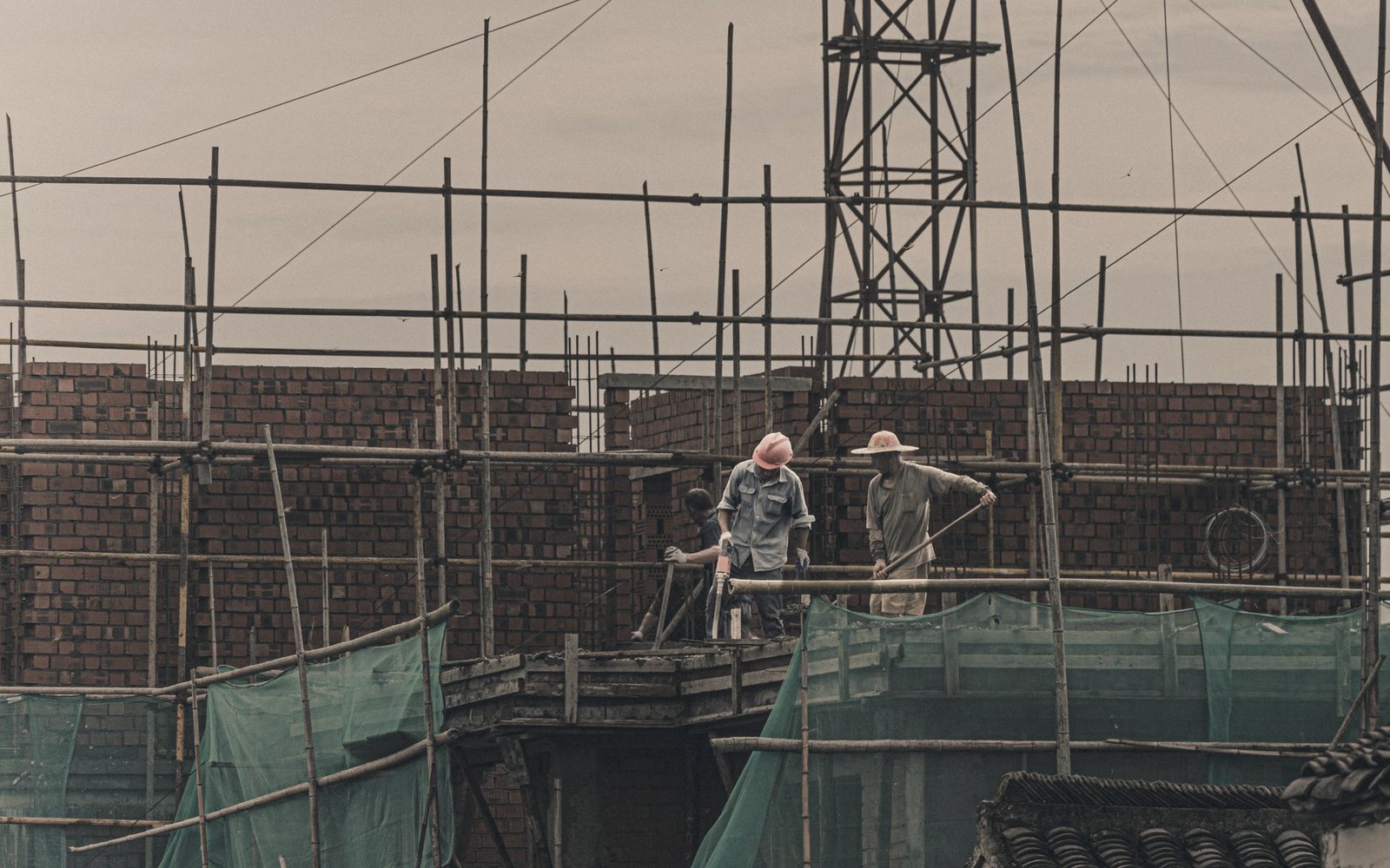 Temporary photograph of construction workers on scaffolding beside a brick wall