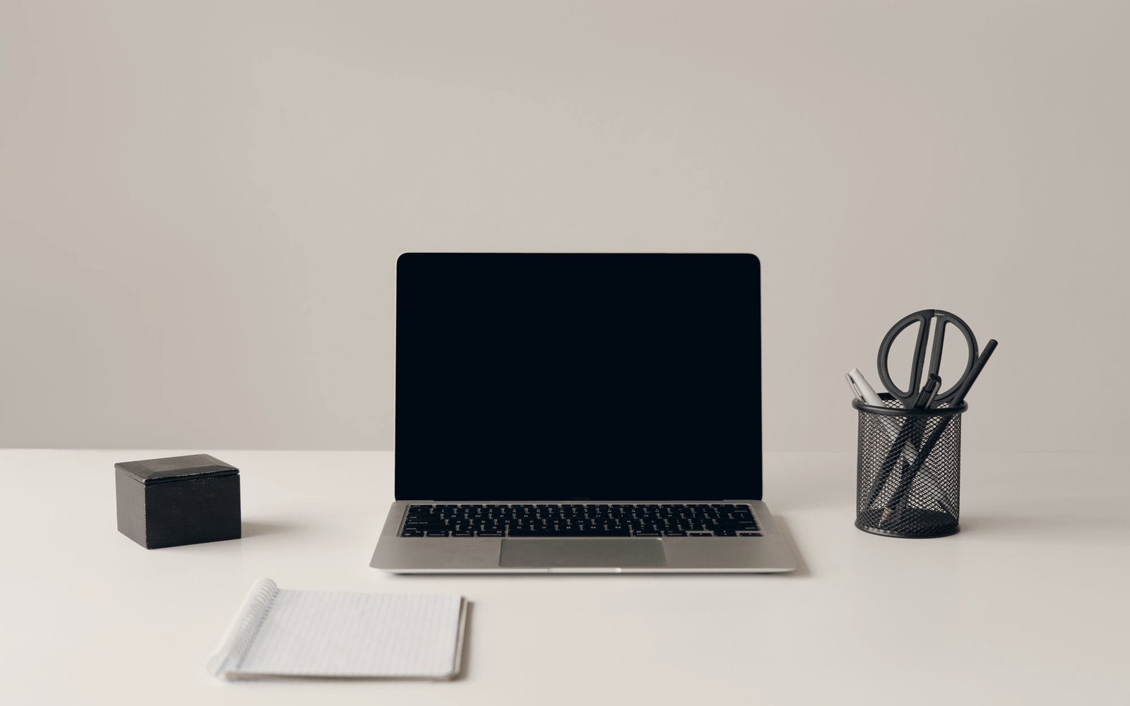Temporary photograph of a minimal studio desk with a laptop, notebook and stationery