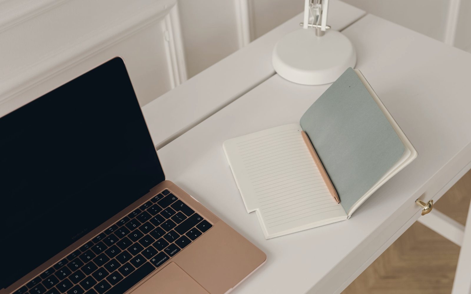 Temporary photograph of a laptop and notebook on a clean studio desk