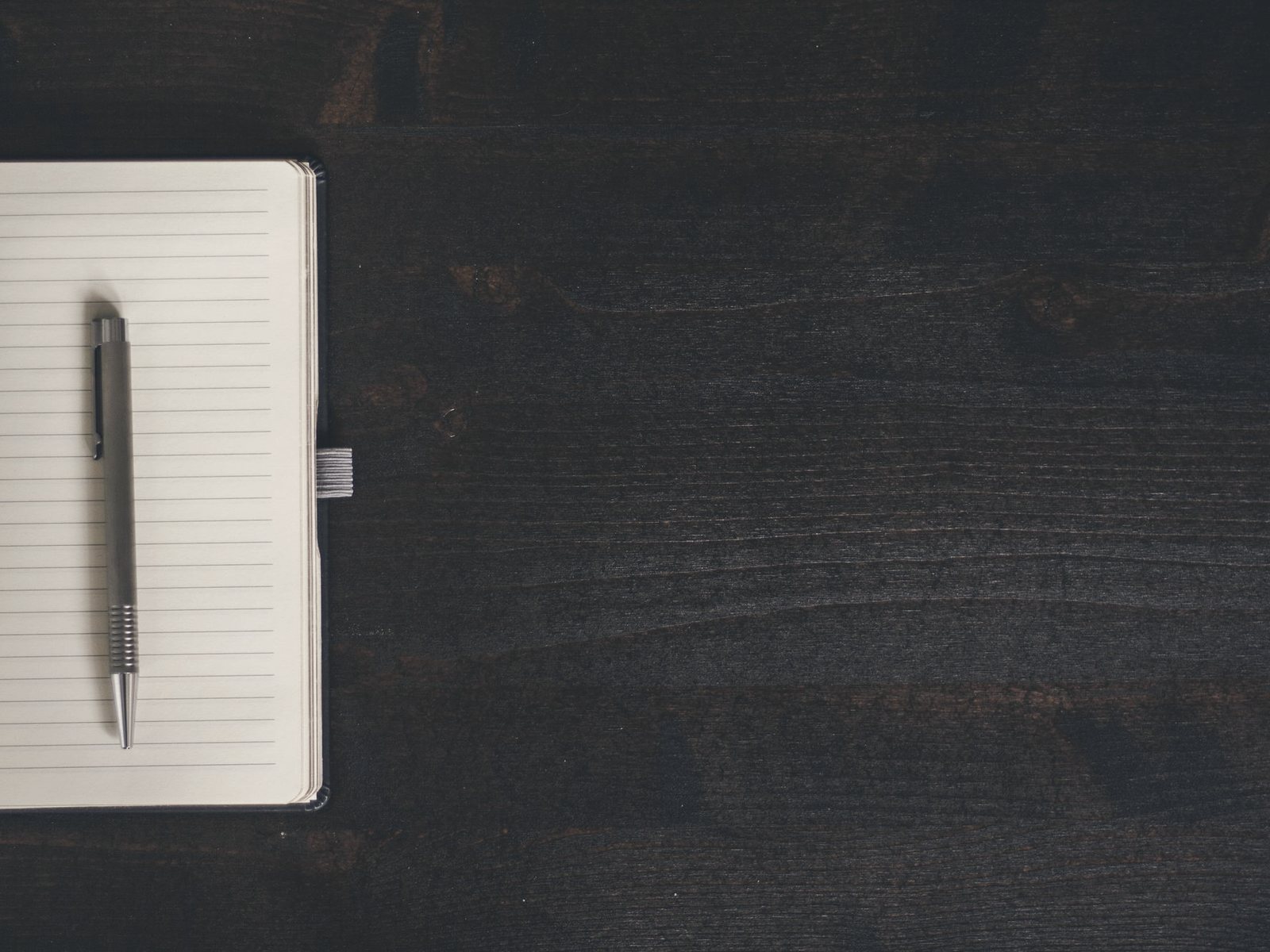 Temporary photograph of an open notebook and pen on a timber desk